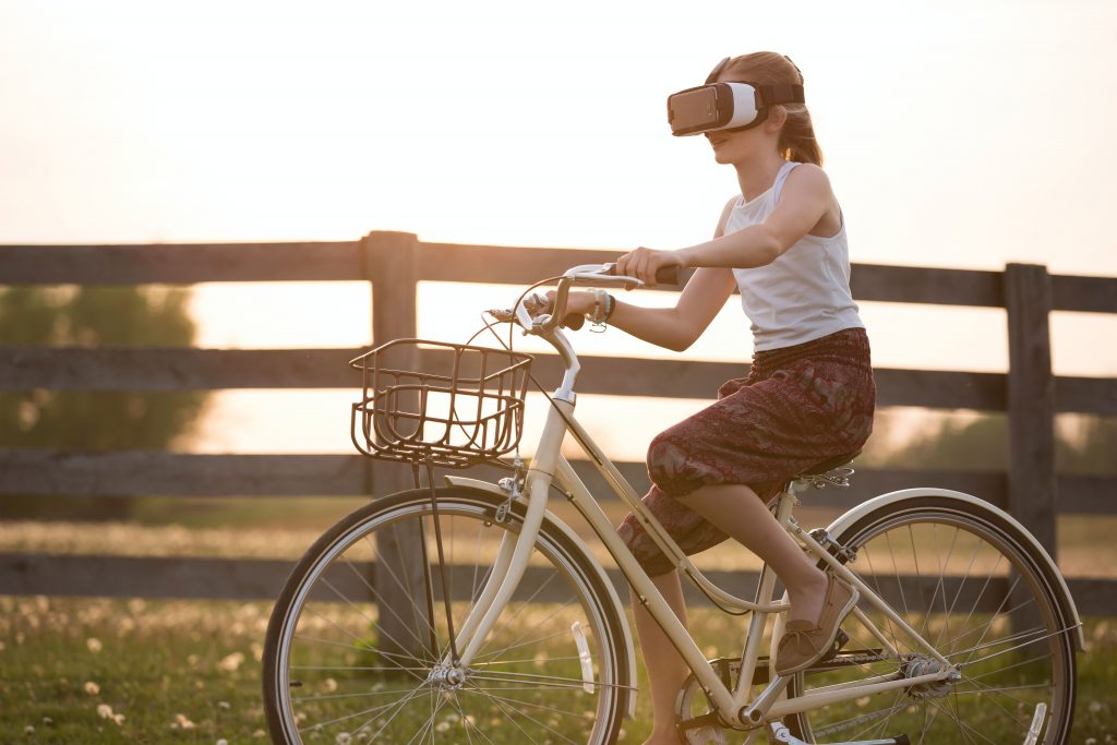 mulher pedalando bicicleta no campo com óculos de realidade virtual metaverso em seus olhos
